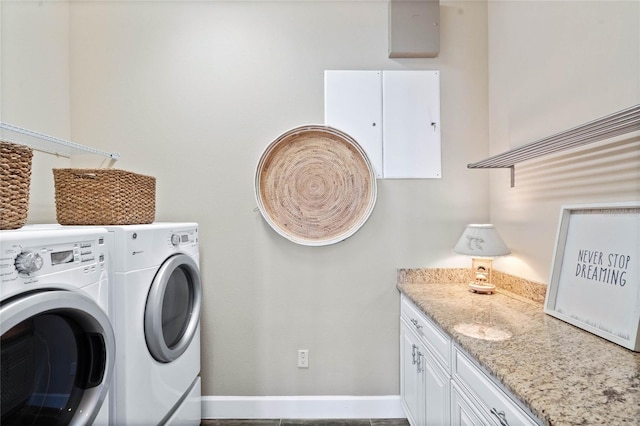 laundry area featuring tile patterned flooring, washer and clothes dryer, and cabinets