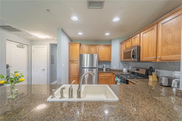 kitchen featuring dark stone countertops, sink, and stainless steel appliances