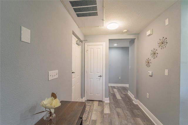 corridor with hardwood / wood-style floors and a textured ceiling