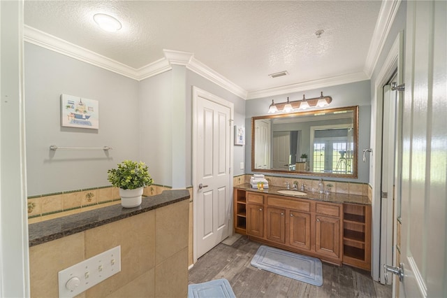 bathroom with hardwood / wood-style flooring, ornamental molding, vanity, and a textured ceiling