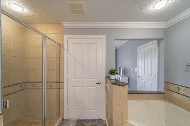 bathroom featuring hardwood / wood-style flooring, crown molding, shower with separate bathtub, and a textured ceiling