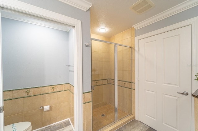 bathroom featuring tile walls, wood-type flooring, a shower with shower door, and toilet