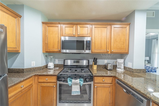 kitchen featuring appliances with stainless steel finishes and dark stone counters