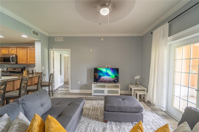 living room featuring crown molding, a wealth of natural light, and light wood-type flooring