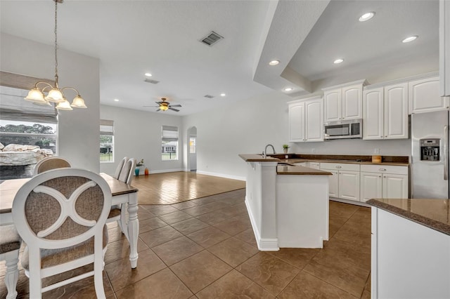 kitchen featuring appliances with stainless steel finishes, ceiling fan with notable chandelier, white cabinetry, and hanging light fixtures