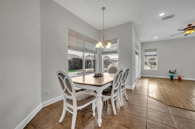 tiled dining room with ceiling fan with notable chandelier