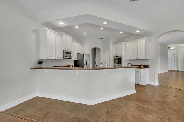 kitchen featuring kitchen peninsula, stainless steel appliances, white cabinetry, and light tile patterned flooring