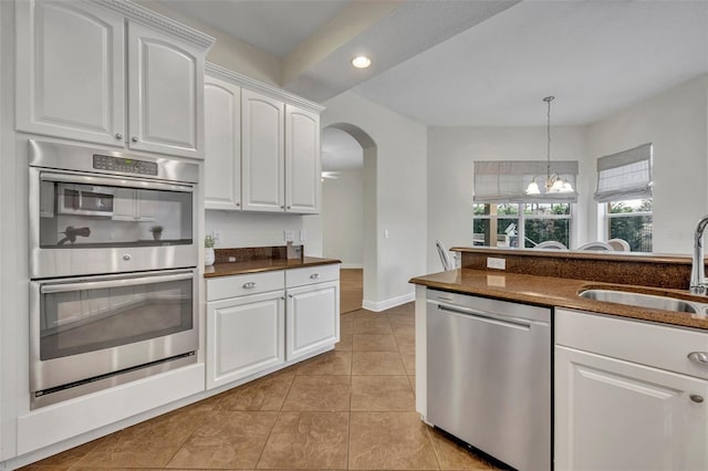 kitchen featuring stainless steel appliances, sink, light tile patterned floors, white cabinets, and hanging light fixtures