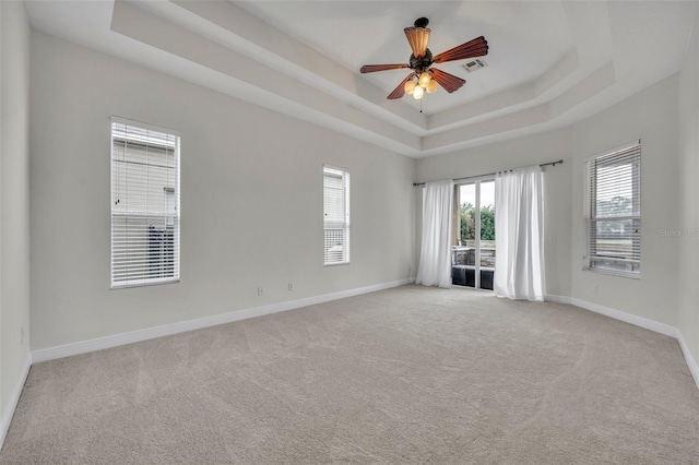 carpeted empty room with a tray ceiling and ceiling fan