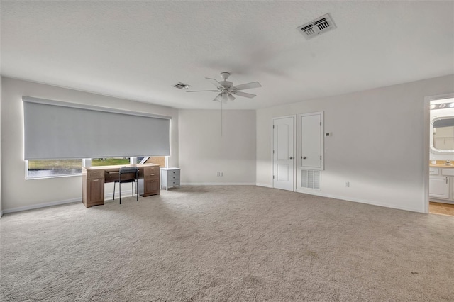 unfurnished room with a textured ceiling, light colored carpet, and ceiling fan