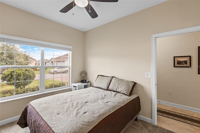 bedroom featuring ceiling fan, multiple windows, and light tile patterned floors