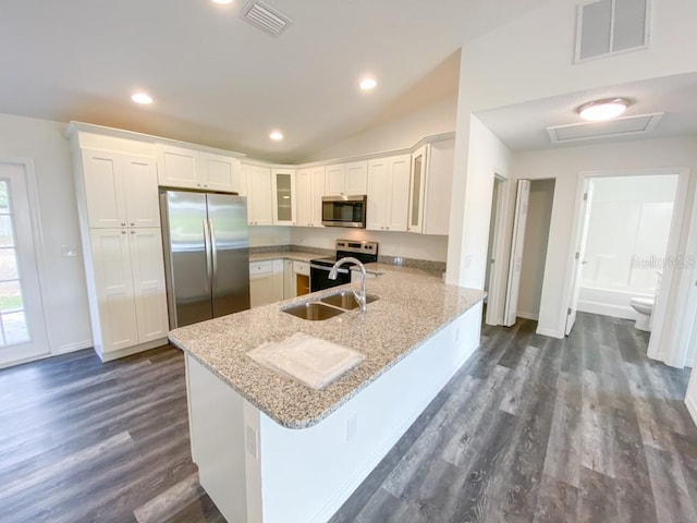 kitchen with appliances with stainless steel finishes, sink, white cabinets, light stone counters, and kitchen peninsula