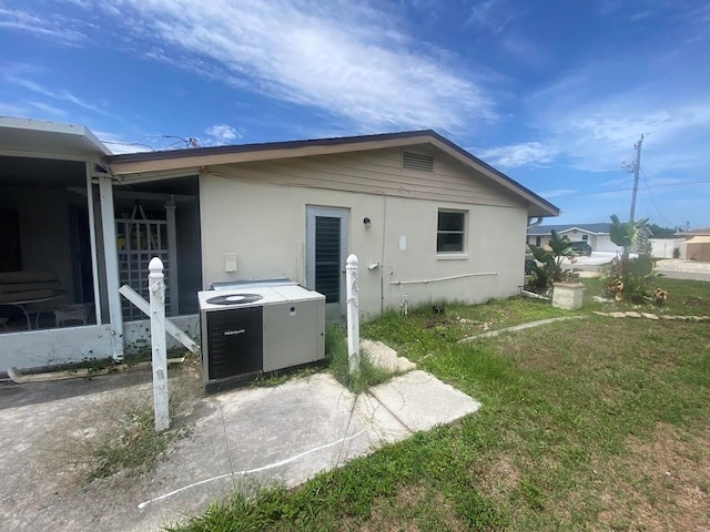 back of house with central AC and a lawn