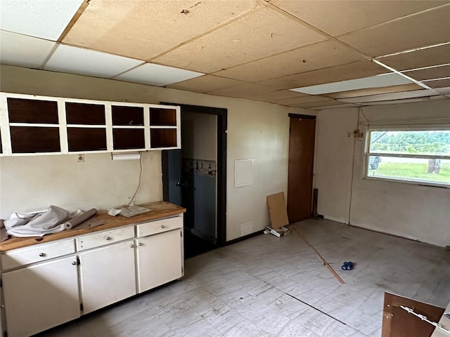 kitchen featuring white cabinets and a drop ceiling