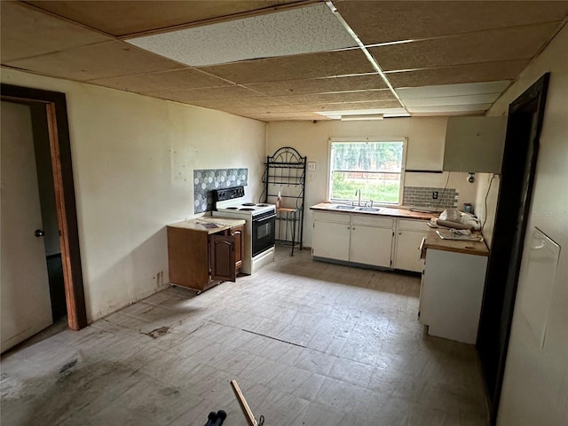 kitchen featuring white cabinets, a drop ceiling, white range with electric cooktop, and sink