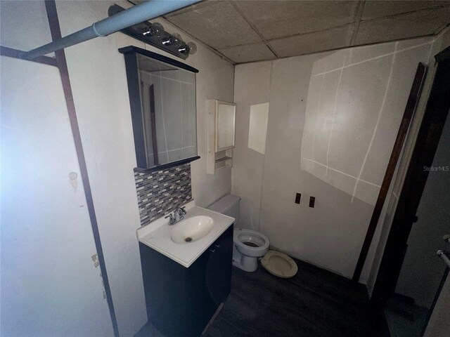 bathroom featuring backsplash, a drop ceiling, toilet, and vanity