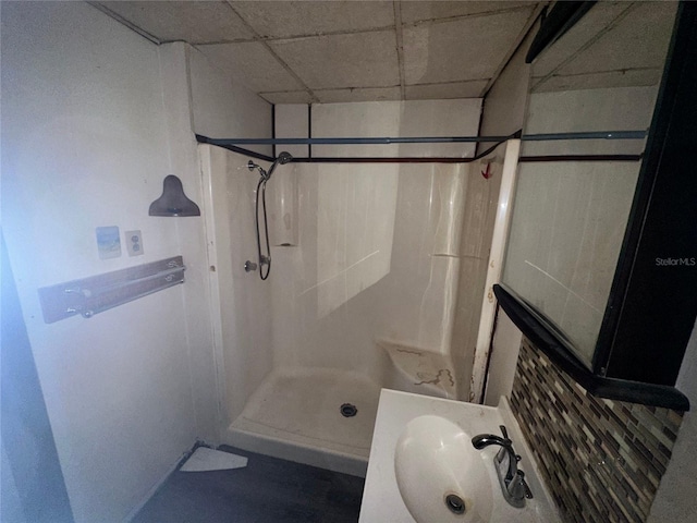 bathroom with a shower, sink, and a drop ceiling