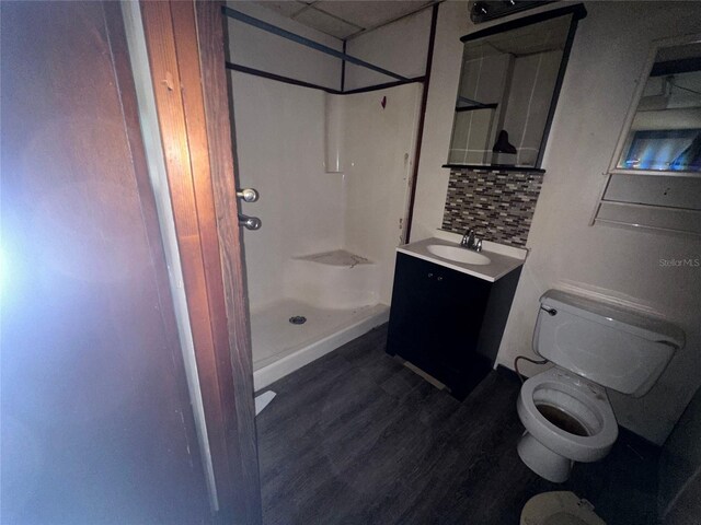 bathroom featuring vanity, wood-type flooring, tasteful backsplash, a shower, and toilet