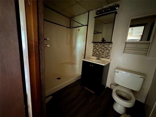 bathroom featuring tasteful backsplash, hardwood / wood-style floors, toilet, a shower, and vanity