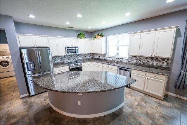 kitchen featuring sink, washer / clothes dryer, white cabinetry, a center island, and stainless steel appliances