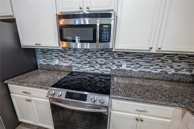 kitchen featuring white cabinets, stainless steel appliances, dark stone countertops, and decorative backsplash