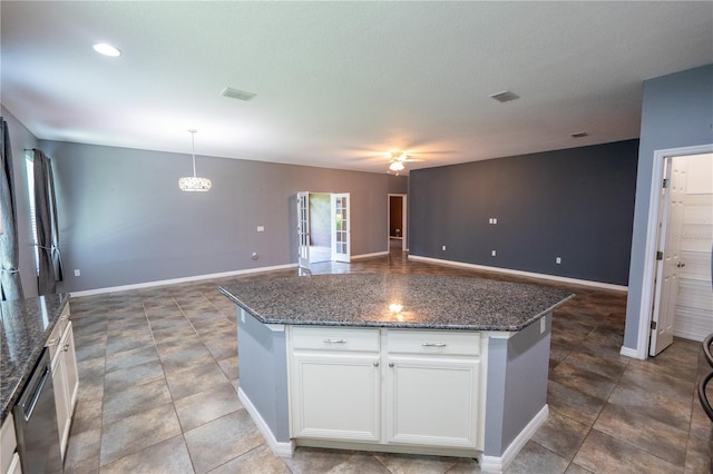 kitchen featuring white cabinetry, stainless steel dishwasher, a center island, and hanging light fixtures