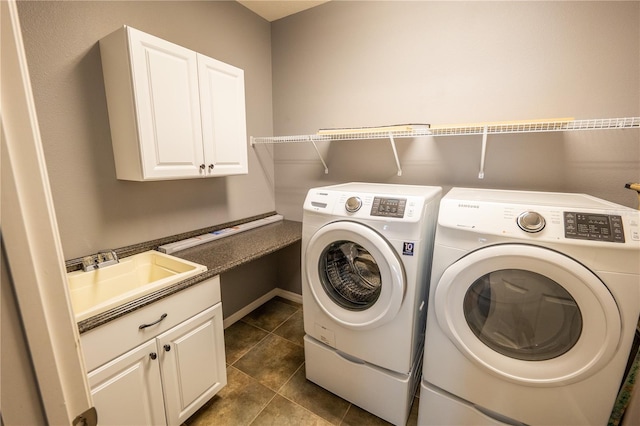 laundry area featuring cabinets, dark tile patterned flooring, washer and clothes dryer, and sink