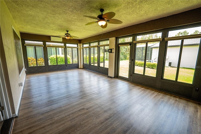 unfurnished sunroom with ceiling fan, an AC wall unit, and a wealth of natural light