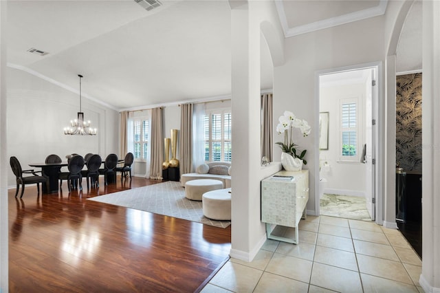 living room featuring an inviting chandelier, ornamental molding, and light tile patterned floors