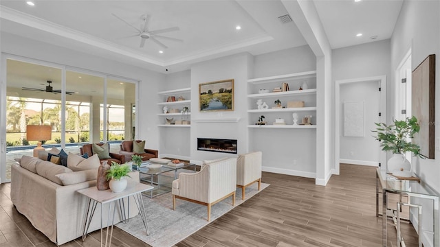 living room featuring wood-type flooring, built in features, and ceiling fan