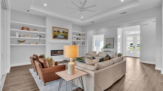 living room with a tray ceiling, ceiling fan, hardwood / wood-style flooring, and crown molding