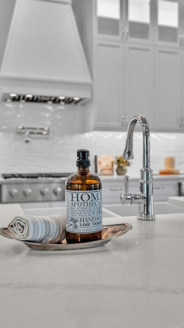 room details featuring white cabinets, premium range hood, and backsplash