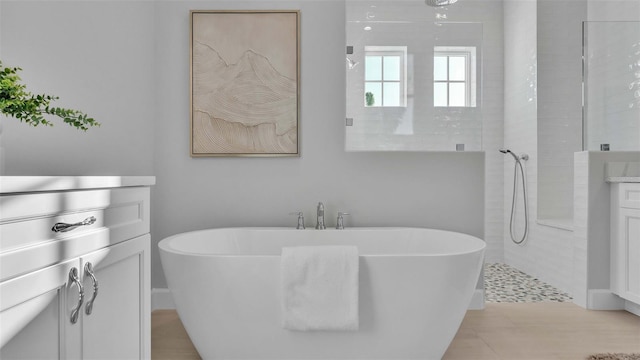 bathroom featuring tile patterned flooring, vanity, and plus walk in shower