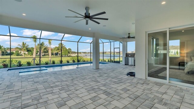 view of swimming pool with glass enclosure, a water view, ceiling fan, and a patio