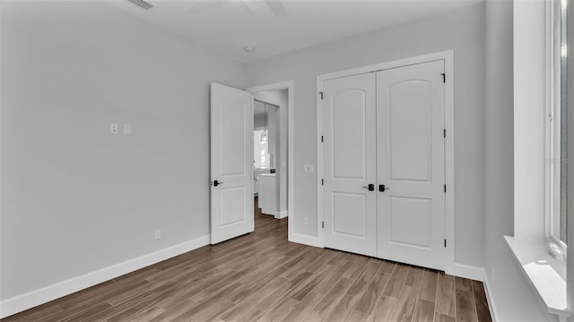 unfurnished bedroom with ceiling fan, light hardwood / wood-style flooring, and a closet