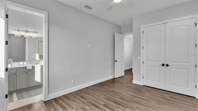 unfurnished bedroom with ceiling fan, a closet, light hardwood / wood-style flooring, and ensuite bathroom