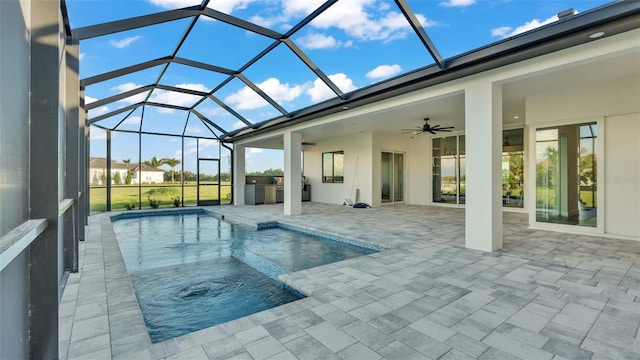 view of pool with a patio, glass enclosure, and ceiling fan