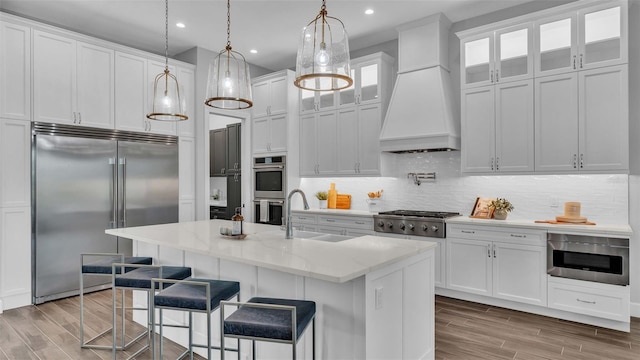 1529 Rio Vista Ter, Parrish, FL 34219 - kitchen with custom range hood, a sink, light wood-style floors, stainless steel appliances, and white cabinetry