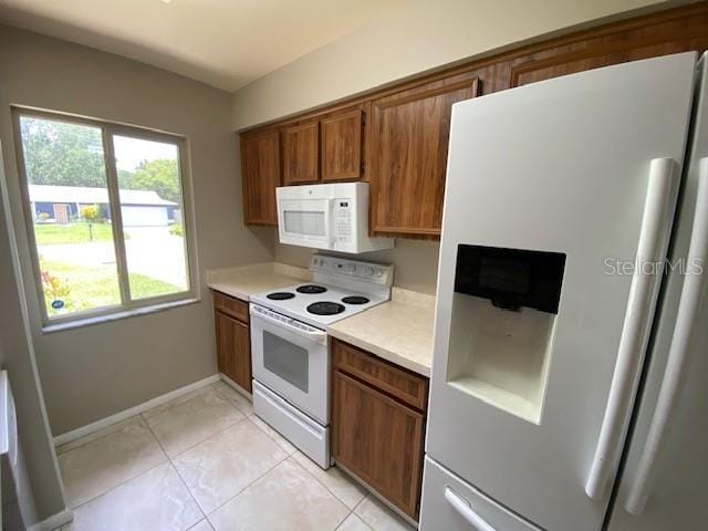 kitchen with white appliances, a healthy amount of sunlight, and light tile patterned floors