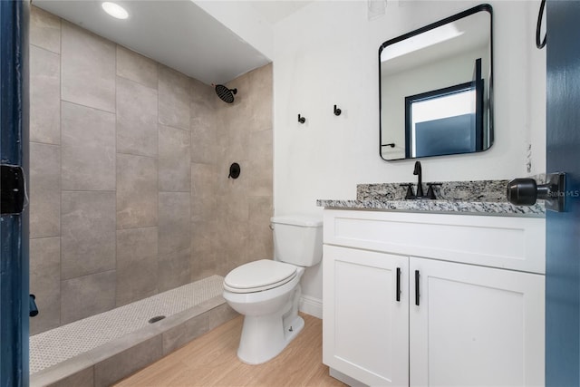 bathroom featuring toilet, wood finished floors, vanity, baseboards, and a shower stall