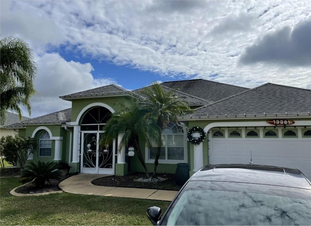 view of front of home with stucco siding, concrete driveway, an attached garage, and a shingled roof