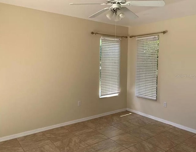 empty room featuring a healthy amount of sunlight, baseboards, and a ceiling fan