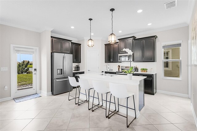 kitchen featuring a kitchen island with sink, decorative light fixtures, a kitchen bar, and stainless steel appliances