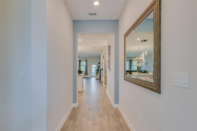 hall with light hardwood / wood-style flooring and a chandelier