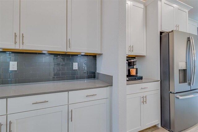 kitchen featuring white cabinets, stainless steel fridge, and tasteful backsplash