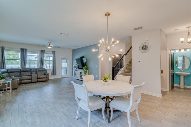 dining area featuring light hardwood / wood-style floors and ceiling fan with notable chandelier