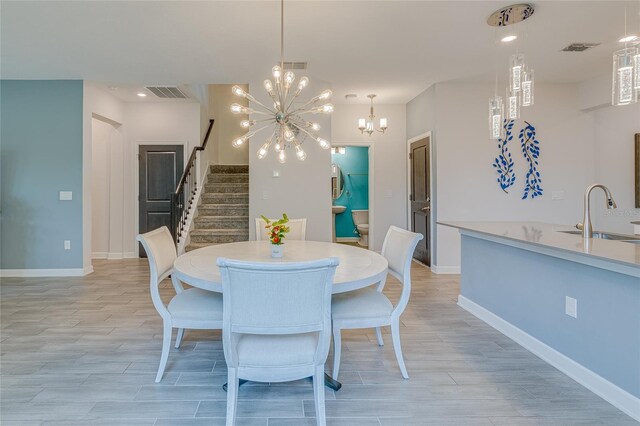 dining room with a notable chandelier, sink, and light wood-type flooring