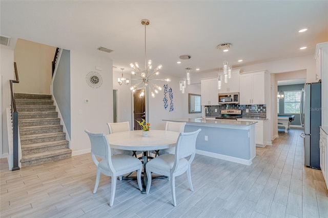 dining space with an inviting chandelier, sink, and light wood-type flooring