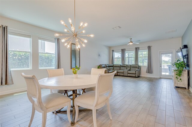 dining space with light wood-type flooring, ceiling fan with notable chandelier, and a wealth of natural light