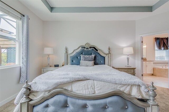 bedroom featuring ensuite bath, light tile patterned floors, and a raised ceiling